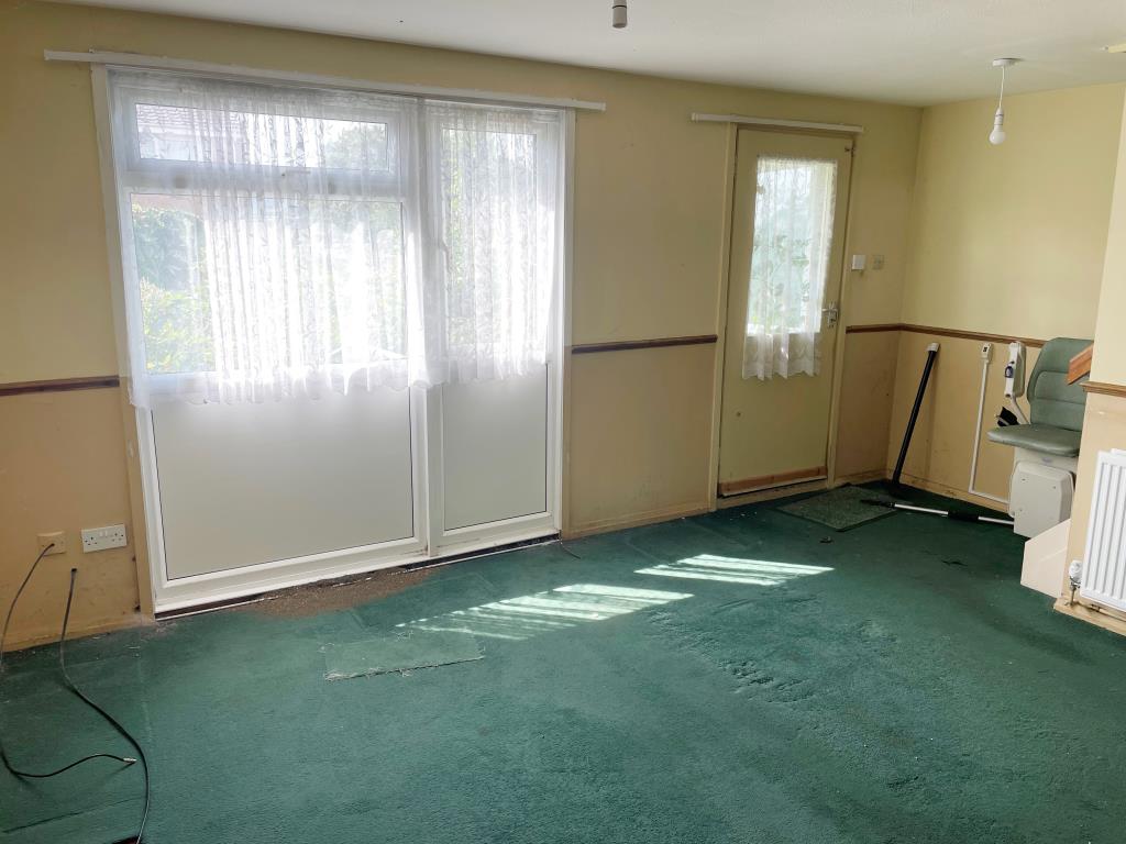 Lot: 19 - END-TERRACE HOUSE IN NEED OF REFURBISHMENT - Living room to rear with door to garden